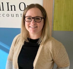 A photo of Sadie Jay in front of an All in One Accounting sign